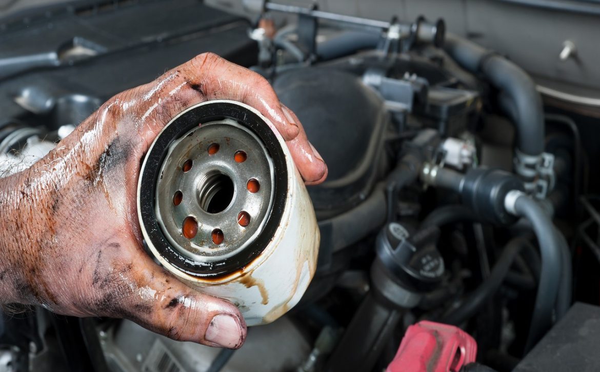Auto mechanic holding oil filter